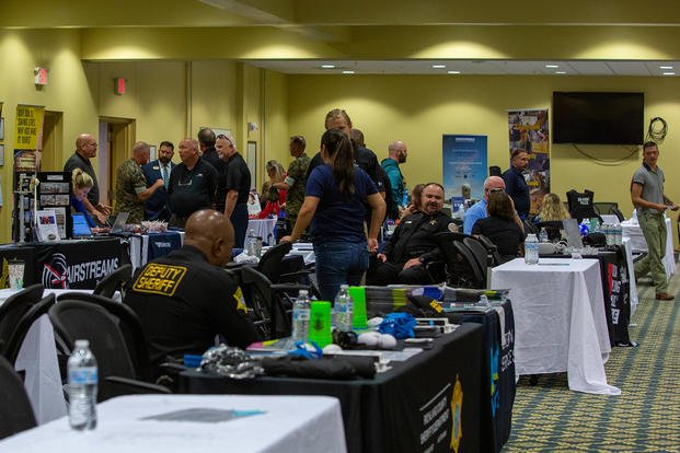 Veterans and service members speak with business representatives about job opportunities at a job fair.