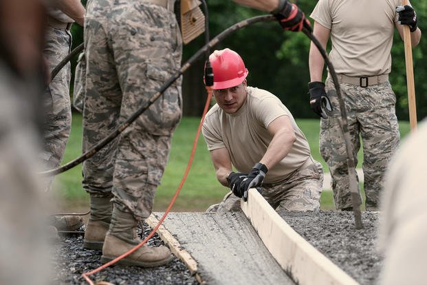 Airmen assigned to the 107th Civil Engineer Squadron, 107th Attack Wing, New York Air National Guard, Niagara Falls Air Reserve Station, N.Y., pour concrete as part of creating a new deliver ramp that is compliant with the Americans with Disabilities Act at Keller Hall at the West Virginia School for the Blind and Deaf, Romney, W.Va.