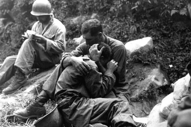 An American soldier comforts his comrade during World War II.