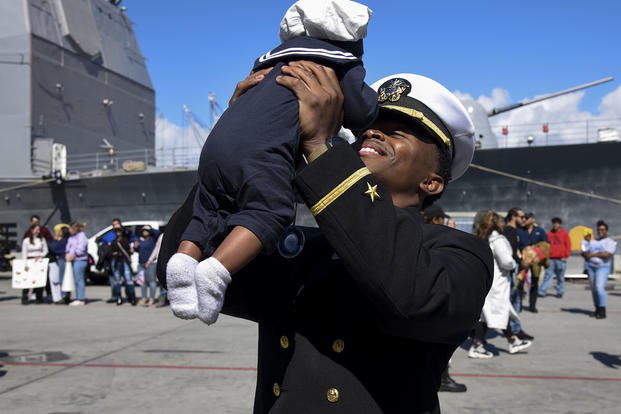 Ensign Lonni Williams meets his newborn child for the first time after completing a seven-month deployment aboard amphibious dock landing ship USS Pearl Harbor (LSD 52).