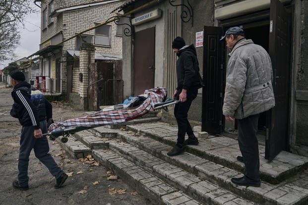 Local residents carry the body of a 20-year-old man killed in Russian shelling in Kherson, Ukraine