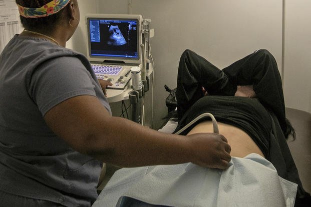 An operating room technician performs an ultrasound on a patient.