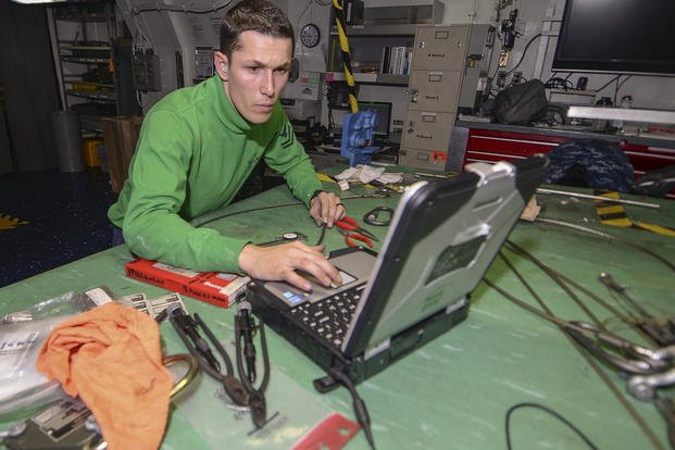 An aviation structural mechanic second class reads maintenance instructions on a laptop computer while conducting aircraft equipment maintenance aboard the amphibious assault ship USS Makin Island.
