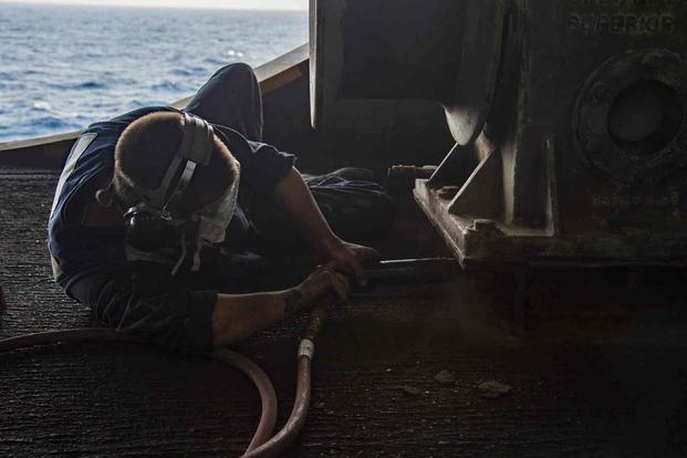 Navy sailor needle guns a gypsy winch.