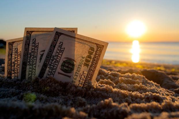 100-dollar bills are stuck in the sand at the beach