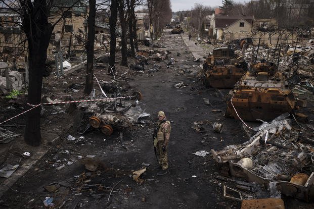 A Ukrainian serviceman stands amid destroyed Russian tanks in Bucha.