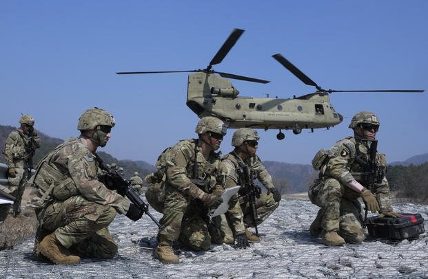 U.S. Army soldiers wait to board their CH-47 Chinook helicopter.