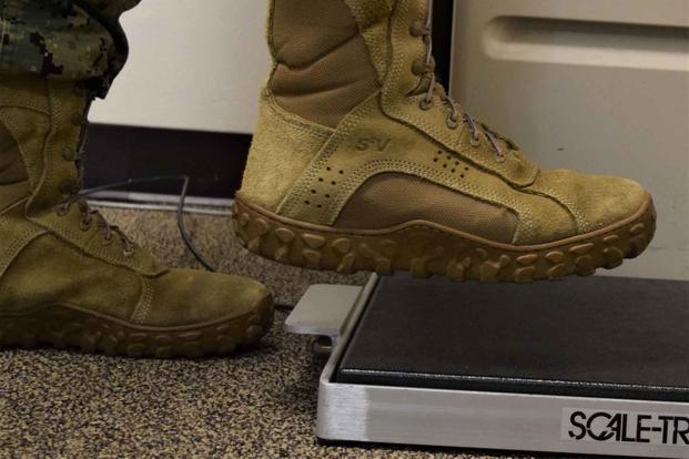 Navy sailor steps on scale with boots on.