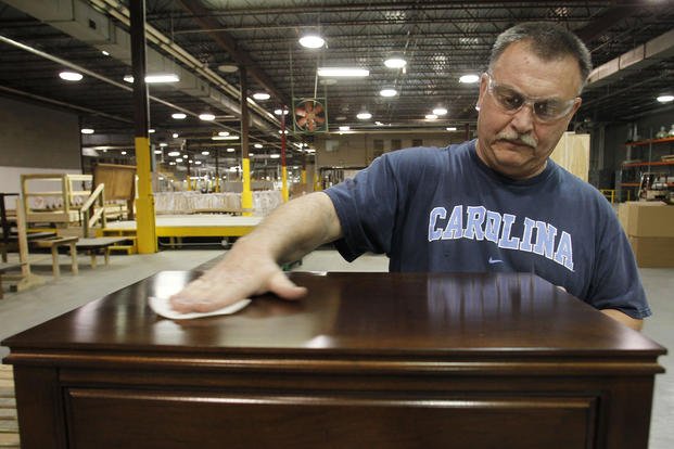Dean Hoyle wipes down the top of a nightstand before packaging it for delivery at the Lincolnton Furniture Company in Lincolnton, N.C.