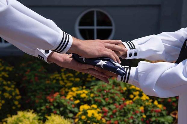 Sailors aboard the USS George Washington pass the flag.