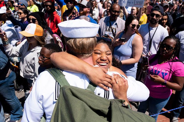 woman hugs sailors as they return from deployment with the USS George H.W. Bush at Naval Station Norfolk