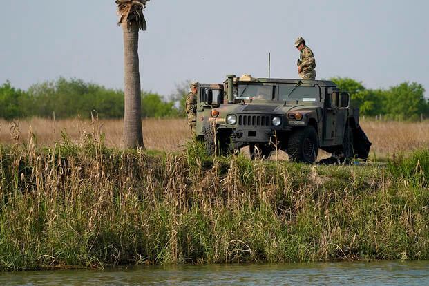 Members of the National Guard stand near a vehicle along the U.S.-Mexico border in Mission, Texas. 