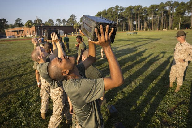 male U.S. Marine Corps recruits train with weighted ammo cans