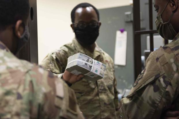 A U.S. Air Force deputy disbursing officer shows a stack of U.S. currency