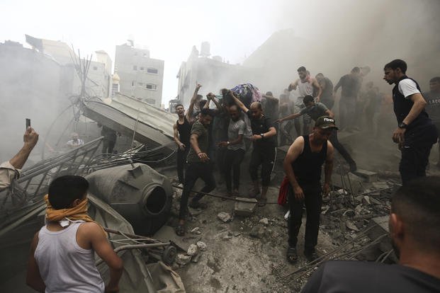 Palestinians remove a dead body from the rubble of a building after an Israeli airstrike