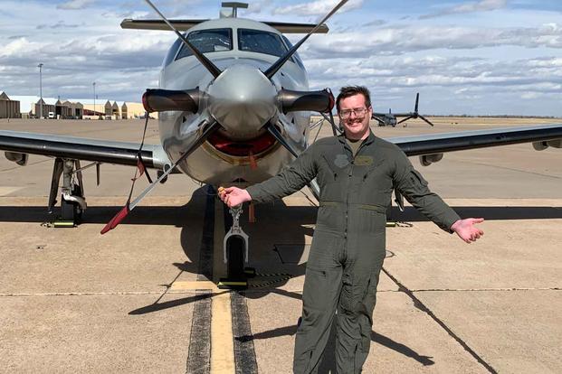 Senior Airman Sean Ryan Stevenson poses in front of an airplane