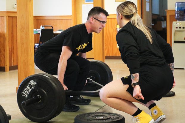 1st Lt. Lindsey Boughter, a public affairs officer with the Pennsylvania Army National Guard and a state powerlifting record-holder, demonstrates proper deadlifting techniques to Staff Sgt. Zane Craig.