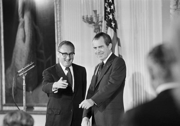 Secretary of State Henry Kissinger gestures to the audience in the East Room of the White House