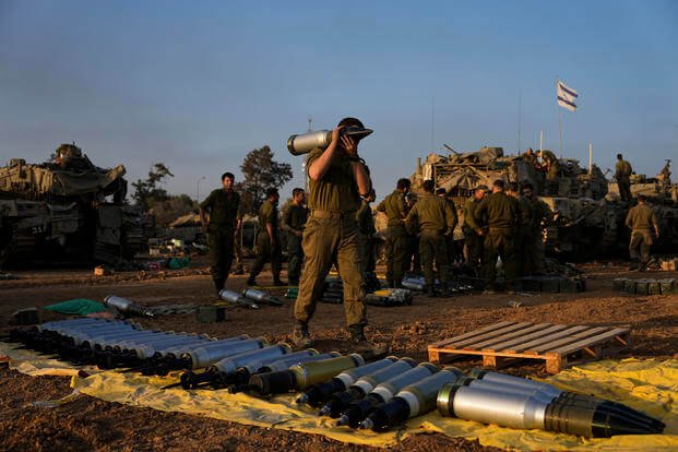 Israeli soldiers load shells onto a tank.