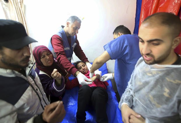 Palestinian medics treat a girl wounded in the Israeli bombardment at a building