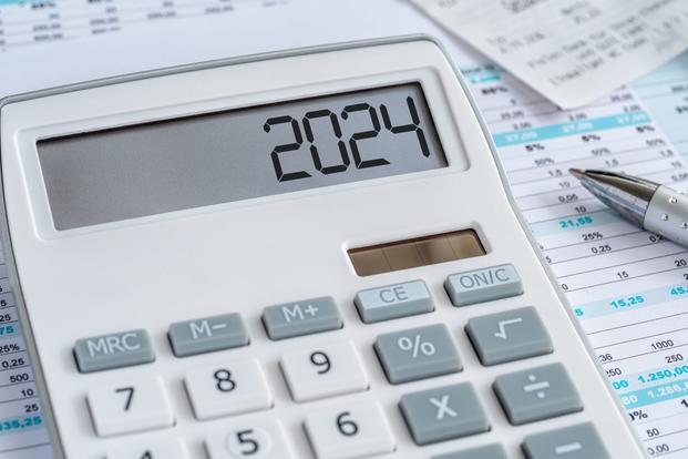 A calculator with "2024" in its display sits on top of some financial charts.