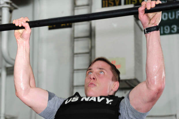 Naval Aircrewman (Tactical Helicopter) 2nd Class Clayton Kimbrough performs a weight-vest pull-up aboard the aircraft carrier USS Theodore Roosevelt.