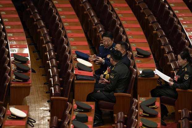 Military delegates chat before the closing session of the National People's Congress at the Great Hall of the People