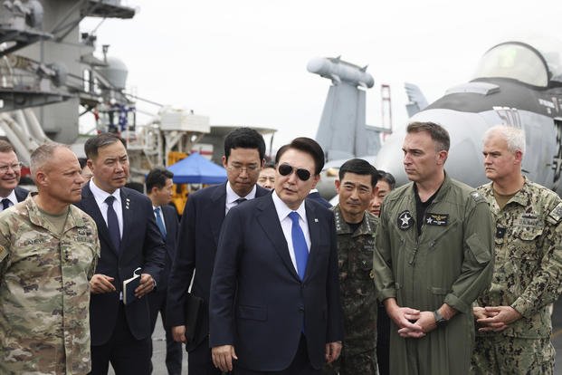 South Korean President Yoon Suk Yeol, center, boards the USS Theodore Roosevelt