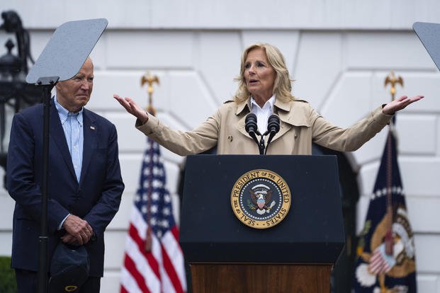 President Joe Biden listens as first lady Jill Biden speaks during a barbecue