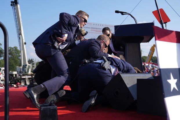 Former President Donald Trump is covered by U.S. Secret Service agents at a campaign rally.