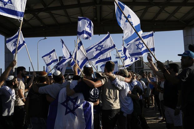 Protesters wave Israeli national flags in support of soldiers being questioned for detainee abuse