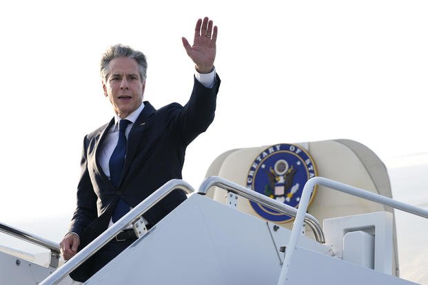 Secretary of State Antony Blinken waves as he boards a plane.