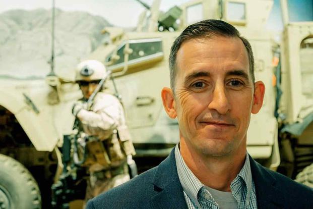 Retired Marine Corps Maj. David McGrath in front of exhibit model