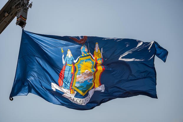 The San Antonio-class amphibious transport dock USS New York (LPD 21) flies its battle flag as the ship departs homeport for deployment.