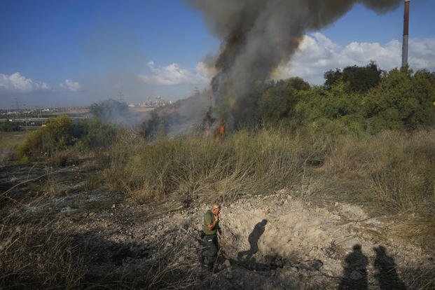 A police officer inspects the area around a fire after the military fired interceptors at a missile.