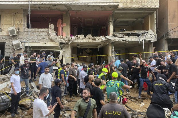 People gather near a damaged building at the scene of an Israeli missile strike. 