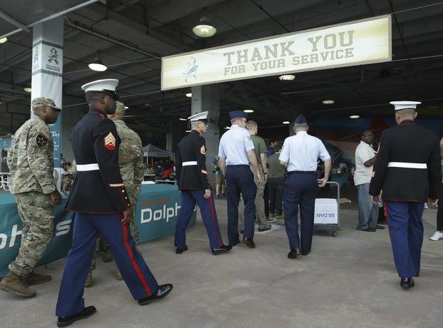 Members of the military enter Hard Rock Stadium before an NFL football game