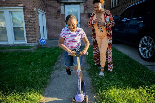 Nicole Bowden watches her daughter Zariah, 7, ride a scooter 