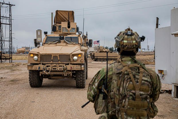 U.S. Soldier walks toward a M2 Bradley Infantry Fighting Vehicle in Syria