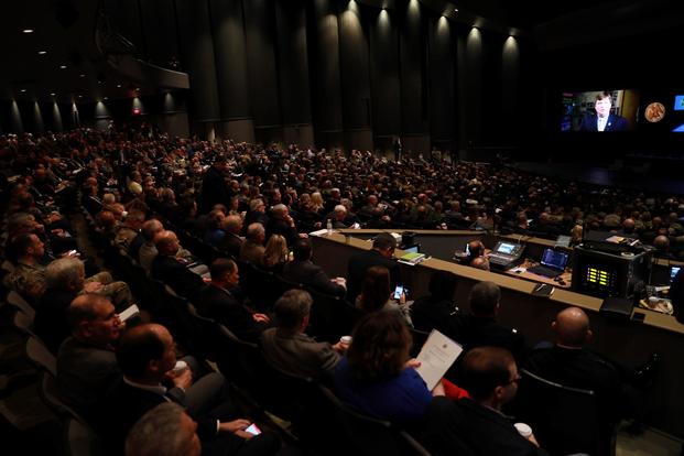 Audience members fill a darkened auditorium.