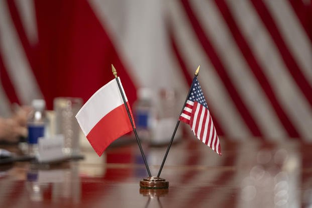 Polish and American flags are displayed during a meeting