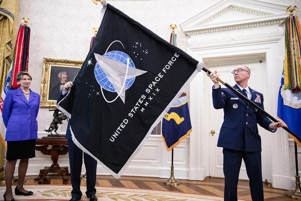 Chief Master Sgt. Roger Towberman, right, Space Force and Command senior enlisted leader, with Secretary of the Air Force Barbara Barrett, present President Donald Trump with the official flag of the United States Space Force in the Oval Office of the White House in Washington, D.C.