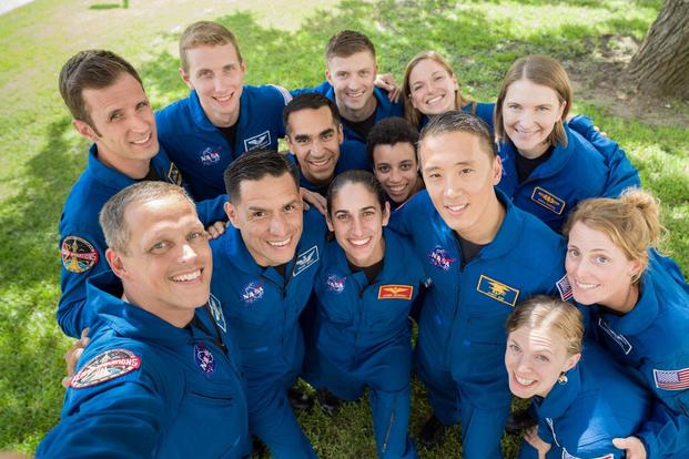 The members of the 2017 NASA Astronaut Class pose for a group selfie in their blue flight suits.