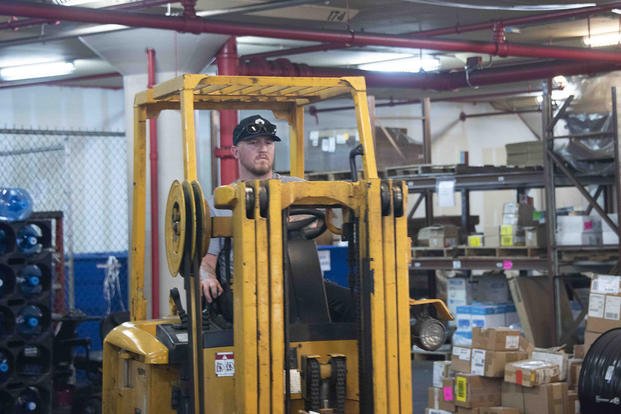 Military Sealift Command (MSC) N48 Supply Chain Management team member Mike Warrenburns uses a forklift to transport parts in the W-143 warehouse at Naval Station Norfolk, Virginia.