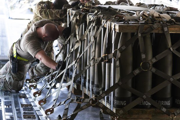  Airmen push over 8,000 pounds of 155 mm shells ultimately bound for Ukraine onto a C-17 aircraft