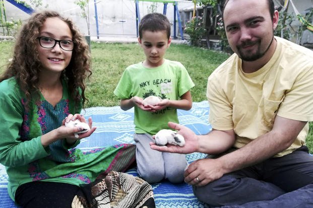 This family photo shows Ryan Corbett holding rabbits with his daughter Miriam and son Caleb in Kabul