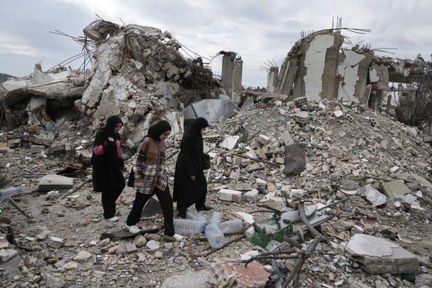 Lebanese citizens pass next to a destroyed house.