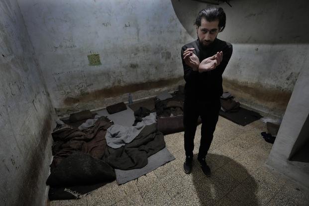 Abdullah Zahra demonstrates how he was tortured in a cell at Branch 215