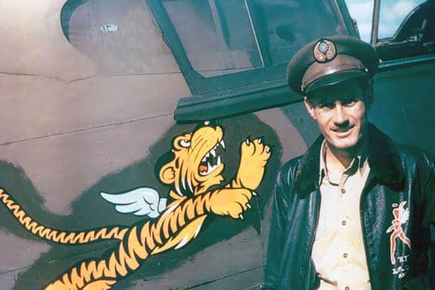 Flight leader and fighter ace Robert ‘R.T.’ Smith stands next to his P-40 fighter at Kunming, China. The ‘Flying Tiger’ insignia was created by the Walt Disney Company. 