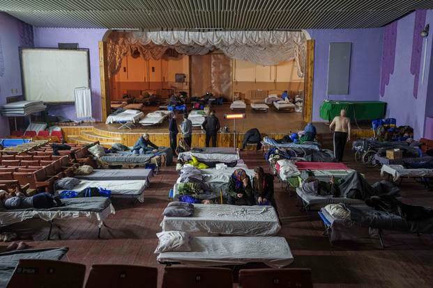 People sit on beds after evacuation from the frontline at a center for displaced people in Pavlohrad